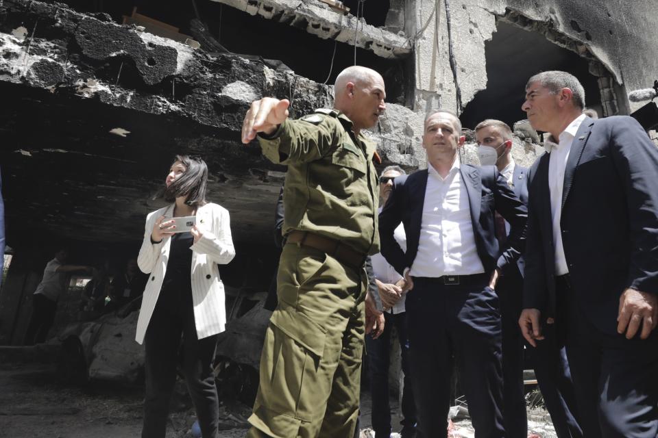 German Foreign Minister Heiko Maas, center, and Israeli Foreign Minister Gabi Ashkenazi, right, visit the site where a rocket hit in the central Israeli city of Petah Tikvah, Thursday, May 20, 2021. (AP Photo/Sebastian Scheiner)