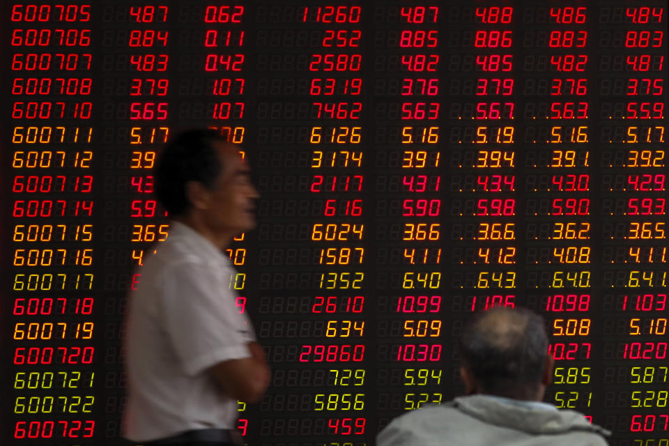 In this Oct. 16, 2019, photo, an investor walks by an electronic board displaying stock prices at a brokerage house in Beijing. Asian shares were mixed Monday, Oct. 21, amid uncertainties about Britain’s exit from the European Union and the ongoing trade conflict (AP Photo/Andy Wong)