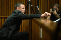 Oscar Pistorius, leans forward in the dock in court in Pretoria, South Africa, Friday, March 14, 2014 on the tenth day of proceedings. Pistorius is charged with the shooting death of his girlfriend Reeva Steenkamp, on Valentines Day in 2013. (AP Photo/Phill Magakoe, Pool)