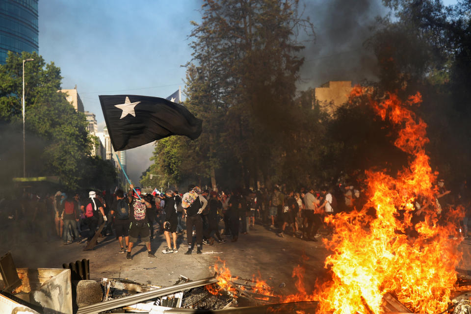 Demonstrators react behind improvised bonfire during an anti-government protest in Santiago, Chile on Oct. 28, 2019. (Photo: Pablo Sanhueza/Reuters)