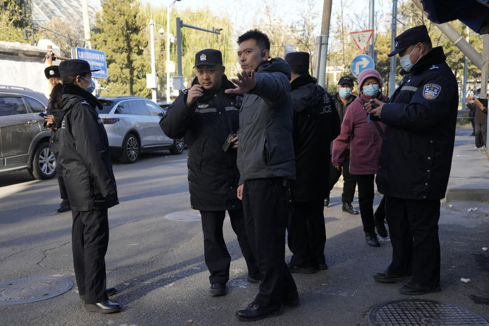 A plainclothes security person directs Chinese police officers near an area cordoned off for journalists near the Chaoyang district court where compensations hearings are held for relatives of passengers on the missing Malaysian Airline MH370 in Beijing, Monday, Nov. 27, 2023. A Beijing court is holding compensation hearings for Chinese relatives of people who died on a Malaysia Airlines plane that disappeared in 2014 on a flight to Beijing. (AP Photo/Ng Han Guan)