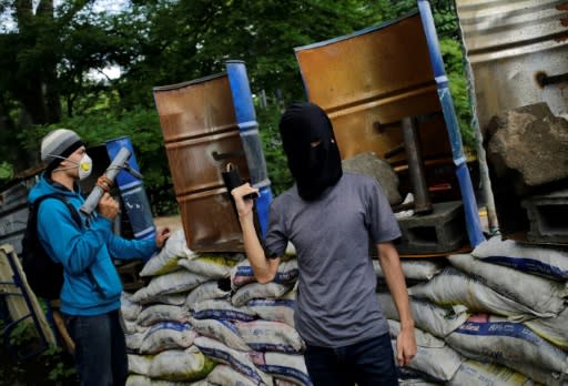 Nicaraguan students with homemade mortars stand guard behind makeshift shields and barricades at Managua's National University (UNAN), days before reporting they were under "attack" from police and paramilitaries