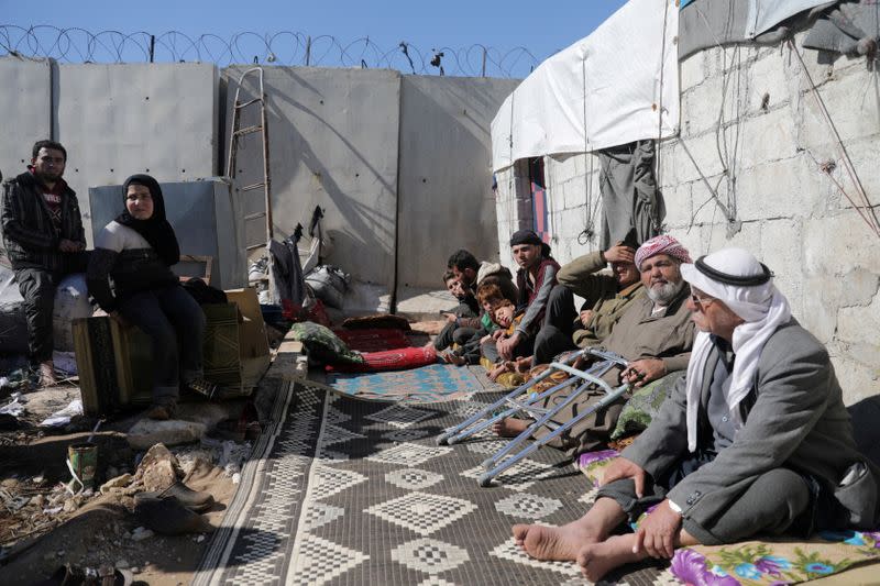 FILE PHOTO: An internally displaced Syrian family sit together outside a tent near the wall in Atmah IDP camp, located near the border with Turkey