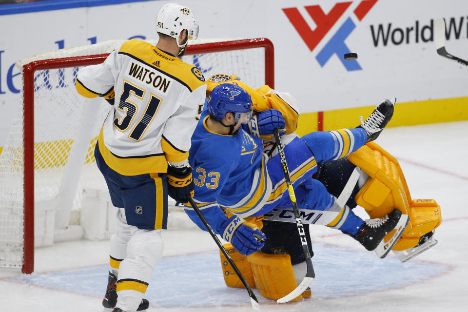 St. Louis Blues' Jordan Kyrou, front center, is tripped up by Nashville Predators goaltender Juuse Saros, back center, of Finland, as Austin Watson defends during the third period of an NHL hockey game Saturday, Feb. 15, 2020, in St. Louis. (AP Photo/Billy Hurst)