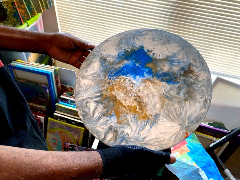Fluid Artist Leroy Bolden holds up one of his circular pour paintings.