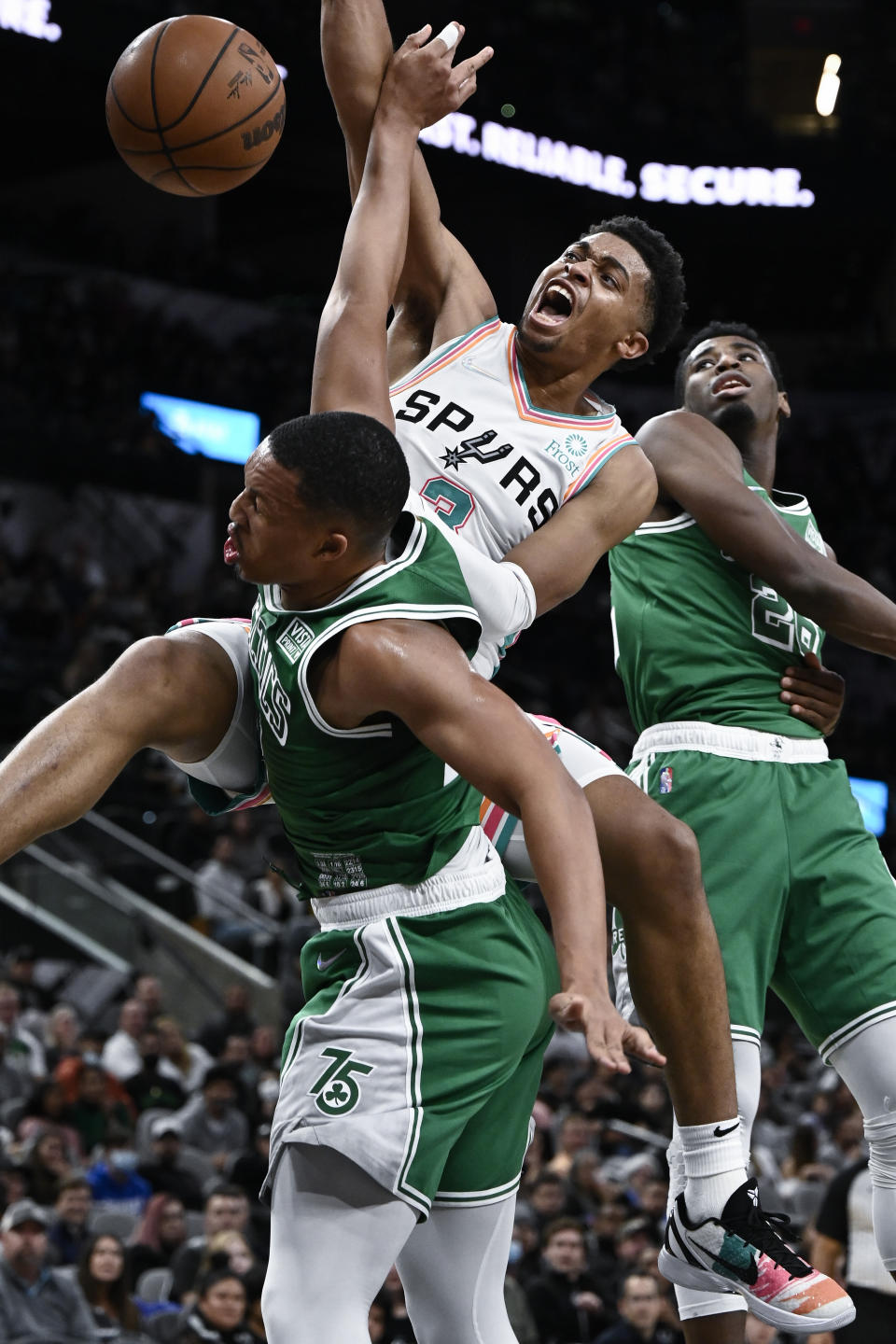 San Antonio Spurs' Keldon Johnson, center, dunks over Boston Celtics' Grant Williams, left, as Boston's Aaron Nesmith watches during the first half of an NBA basketball game Friday, Nov. 26, 2021, in San Antonio. (AP Photo/Darren Abate)