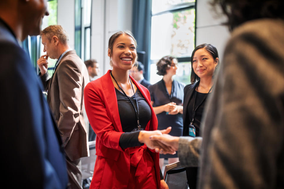 Confident businesswomen handshaking while standing in corridor of an auditorium. 