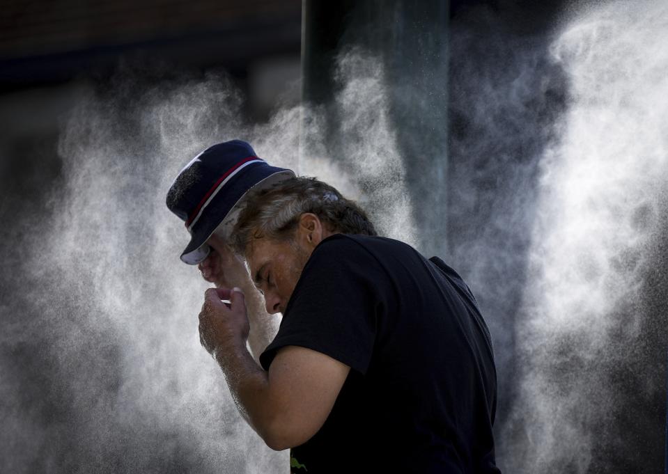 FILE - A man cools off at a temporary misting station deployed by the city in the Downtown Eastside due to a heat wave, in Vancouver, British Columbia, Aug. 16, 2023. UN weather agency says Earth sweltered through the hottest summer ever as record heat in August capped a brutal, deadly three months in northern hemisphere. (Darryl Dyck/The Canadian Press via AP, File)