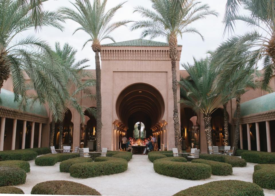 A patio with massive ferns and palm trees in front of a large building.