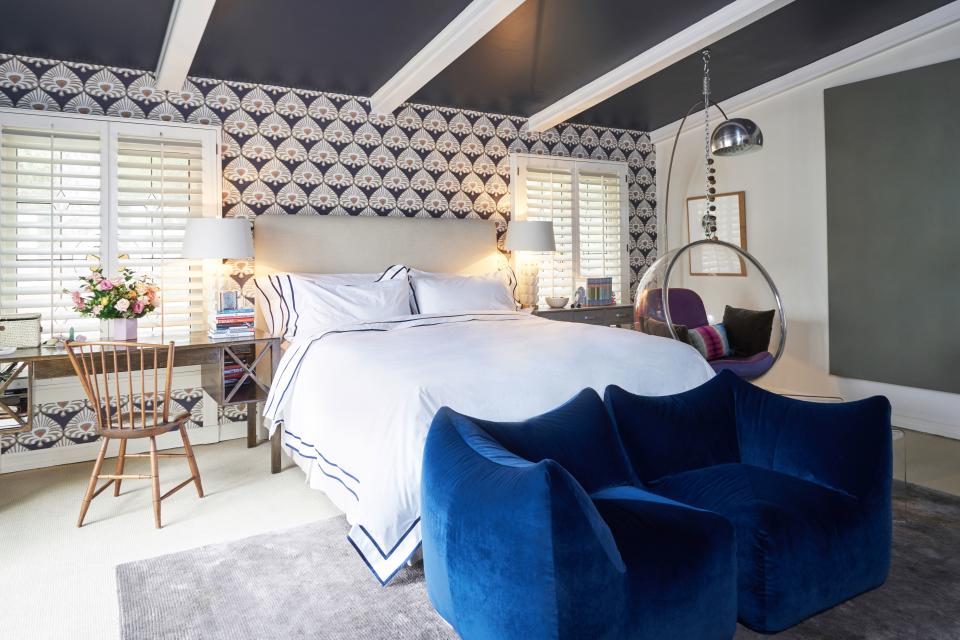 The Serena & Lily Palmetto wallpaper is a crisp contrast to white bedsheets by Matouk for One Kings Lane. An antique English writing desk does double duty as a nightstand.