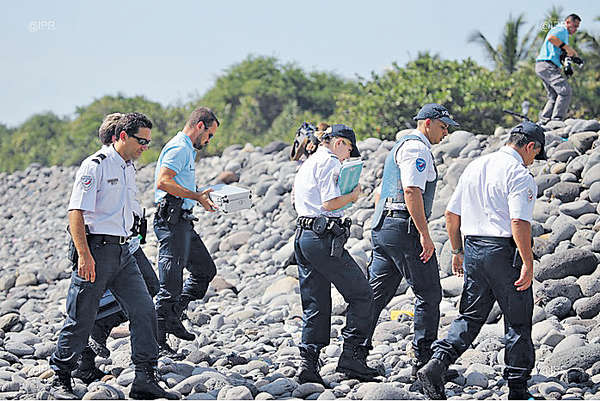 留尼旺島警方在岸邊找到金屬殘骸放入金屬盒取走。