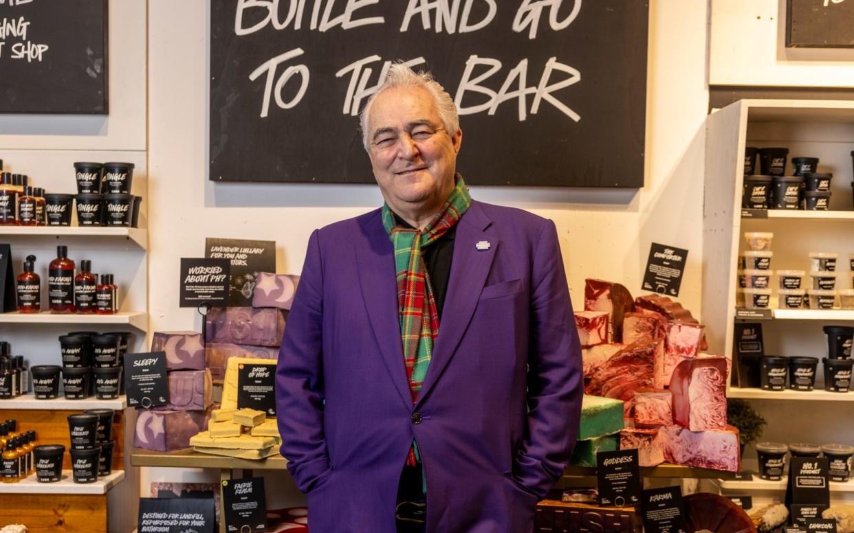 Mark Constantine in a purple suit stood before a display of Lush cosmetics