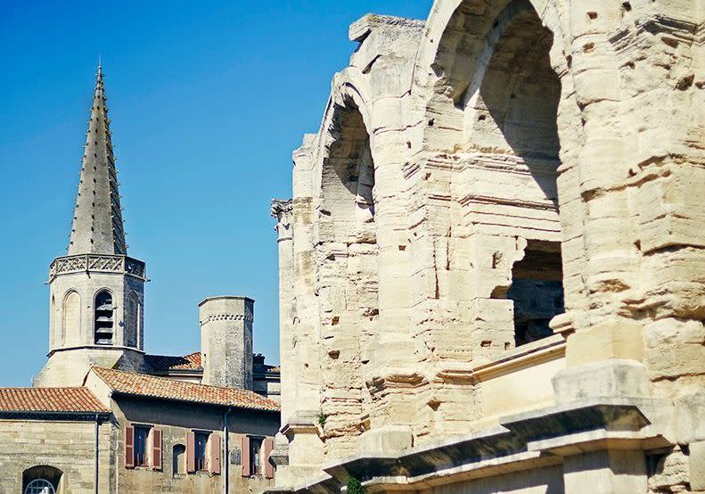 Fille des marais et des étangs, aspirant à la mer, cette ville carrefour blottie dans une boucle du Rhône a toujours été source d’inspiration. Depuis l’Antiquité, par voie terrestre ou fluviale, on s’y presse, on s’y pose, on y rivalise de constructions. Des thermes, des théâtres, des cathédrales hier, une tour ultra-moderne reflétant toutes les lumières de la Provence aujourd’hui... Ce qui fait d’Arles une cité au patrimoine architectural exceptionnel. Huit monuments arlésiens sont d’ailleurs inscrits sur la liste du patrimoine mondial de l’Unesco. De quoi aimanter artistes, poètes et écrivains, et bien sûr photographes, qui ont fait et font la gloire de la capitale de la Camargue. Aux charmes culturels de la ville, qui s’anime régulièrement au rythme des ferias, des Rencontres de la photographie et des nouvelles expositions, s’ajoute un autre atout séduction de taille : la gastronomie.La gastronomie à Arles Car on mange bien, et même très bien, dans la cité qui peut brandir en étendard son fameux saucisson d’Arles, sa daube de taureau et son trident (un petit fromage à pâte molle au lait de brebis). Autour de la ville, La Crau, les Alpilles, les rizières camarguaises, les étangs et le Salin de Giraud nourrissent la carte des restaurants qui se multiplient comme des petits pains, entre musées et hôtels particuliers des 16e et 17e siècles. Après le renouveau du quartier de la Roquette, prisé pour ses ruelles de charme et ses petites places où flâner en terrasse, c’est le quartier de la place Voltaire qui monte. À proximité des récents hôtels Voltaire ou Maison Volver, de nouvelles tables prennent place, à l’instar d’Inari, le futur restaurant de la cheffe Céline Pham qui, venue pour un dîner à quatre mains à la Chassagnette, revenue pour une résidence estivale au Drum Café de la Fondation LUMA, est tombée sous le charme de la ville et ouvrira en juillet un restaurant très attendu. Il n’empêche que c’est maintenant que la ville déploie toute sa douceur de vivre. Courez profiter de ses musées, des terrasses de la place du Forum, de ses néobistrots, de ses institutions gourmandes comme Le Galoubet ou les Maisons Rabanel, savourez une glace maison au bois de réglisse chez Soleileïs, passez prendre l’apéro ou découvrir quelques pépites viticoles chez le Buste et l’Oreille. Échappez-vous le temps d’un repas autour de la piscine de l’hôtel Les Cabanettes, ovni architectural d’inspiration moderniste… Il y a tant à faire, voir, goûter, savourer dans cette cité. Les moustiques ? En attendant de trouver un moyen de les intégrer à la cuisine, on s’en accommode. Mieux, on les assume, comme l’incontournable boutique de création justement baptisée « Moustique », qui vend des mugs clins d’oeil affichant « Piqué à Arles », et un superbe set d’assiettes décorées des insectes emblématiques de la Camargue (moustiquearles.com). Prêt à partir ? Préparer son voyage : rendez-vous sur arlestourisme.com