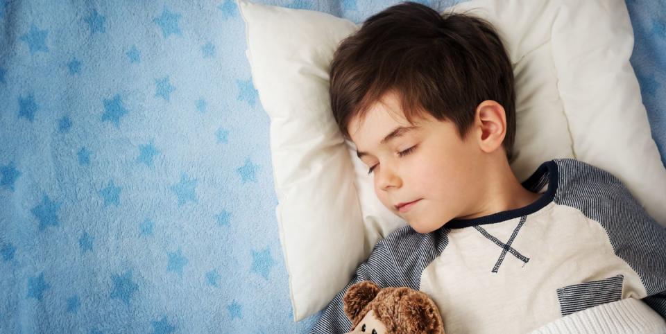 six years old child sleeping in bed with alarm clock