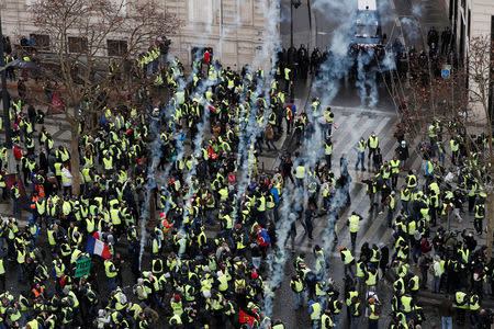 Tear gars floats in the air around protesters wearing yellow vests during clashes with French Gendarmes on the Champs-Elysees Avenue as part of a demonstration by the "yellow vests" movement in Paris, France, December 8, 2018. REUTERS/Benoit Tessier