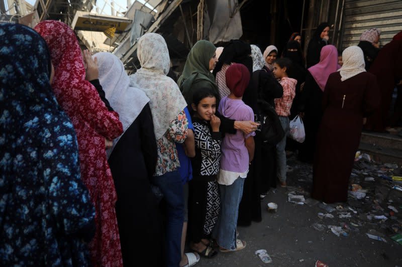 Palestinian women line up to buy fresh bread next to destroyed buildings at the Nuseirat refugee camp in the central Gaza Strip, on Saturday. Photo by Ismael Mohamad/UPI