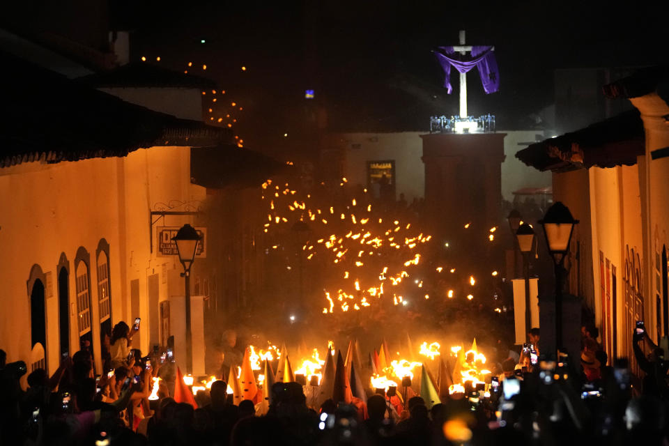 Hooded penitents take part in the Procissao do Fogareu or Torch Procession, in Goias, 350 km, 217 miles, west of Brasilia, Brazil, early Thursday, April 6, 2023. The Holy Thursday procession is a reenactment of Christ's arrest by Roman soldiers represented by "farricocos," who dress in colored robes with cone-shaped hats. (AP Photo/Eraldo Peres)