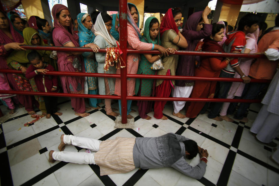 FILE - In this Sunday, March 25, 2012 file photo, a Hindu devotee prostrates as others stand in a queue inside the historical Kali Temple on the third day of the Navratri, or nine nights festival in Jammu, India. Navaratri is a religious occasion in which nine different reincarnated forms of the Goddess Durga are worshipped. (AP Photo/Channi Anand)