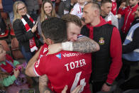 Wrexham's James McClean, left, and Ben Tozer celebrate promotion to League One after the final whistle of the Sky Bet League Two match at the SToK Cae Ras, Wrexham, Saturday April 13, 2024. (Jacob King/PA via AP)