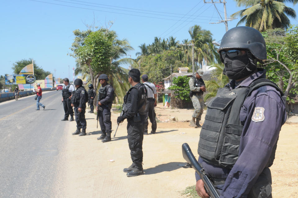 State police stand at a roadblock due to stepped up security after masked armed men broke into a beach home, raping six Spanish tourists who had rented the house in Acapulco, Mexico, Tuesday Feb. 5, 2013. According to the mayor of Acapulco, five masked men burst into a house the Spaniards had rented on the outskirts of Acapulco, in a low-key area near the beach, and held a group of six Spanish men and one Mexican woman at gunpoint, while they raped the Spanish women before dawn on Monday. (AP Photo/Bernandino Hernandez)