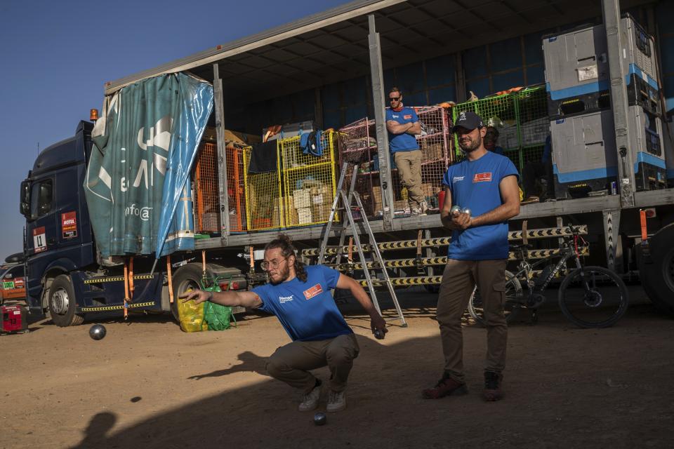 In this Monday, Jan. 13, 2020 photo, Dakar rally staffers play petanque after stage eight in Wadi Al Dawasir, Saudi Arabia. Formerly known as the Paris-Dakar Rally, the race was created by Thierry Sabine after he got lost in the Libyan desert in 1977. Until 2008, the rallies raced across Africa, but threats in Mauritania led organizers to cancel that year's event and move it to South America. It has now shifted to Saudi Arabia. The race started on Jan. 5 with 560 drivers and co-drivers, some on motorbikes, others in cars or in trucks. Only 41 are taking part in the Original category. (AP Photo/Bernat Armangue)