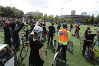 Cyclists raise their fists as they gather at Cal Anderson Park after taking part in the "Ride for Justice," Thursday, June 11, 2020, Seattle. People rode to the park and then took part in a rally to protest against police brutality and racial inequality. (AP Photo/Ted S. Warren)