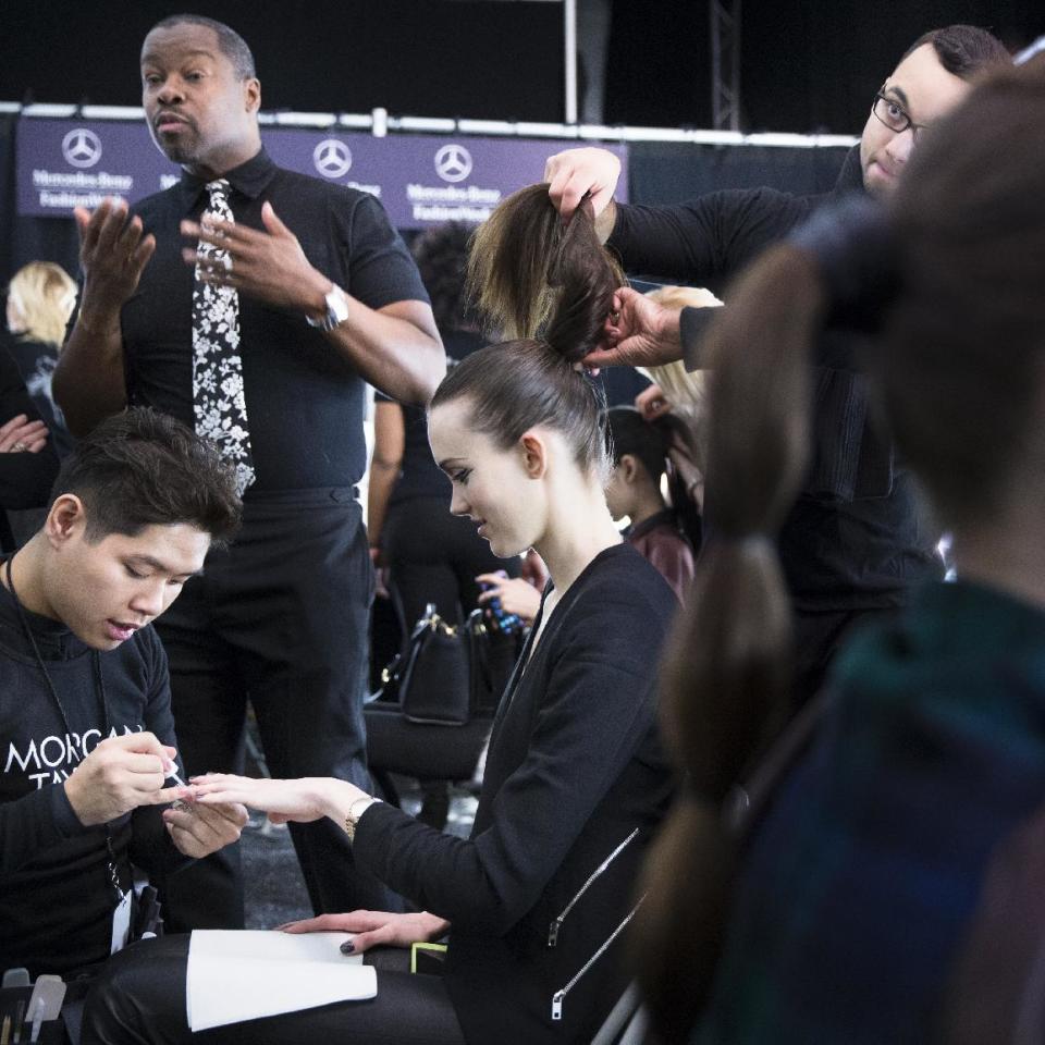 Models have their hair and makeup done backstage before the Carmen Marc Valvo Fall 2014 collection is modeled during Fashion Week, Friday, Feb. 7, 2014, in New York. (AP Photo/John Minchillo)