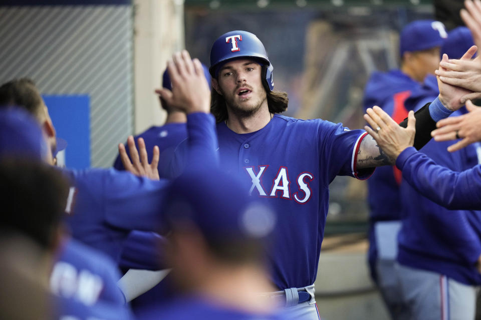Texas Rangers' Jonah Heim, center, is greeted by teammates in the dugout after scoring on a single hit by Leody Taveras during the fourth inning of a baseball game against the Los Angeles Angels, Saturday, May 6, 2023, in Anaheim, Calif. (AP Photo/Jae C. Hong)