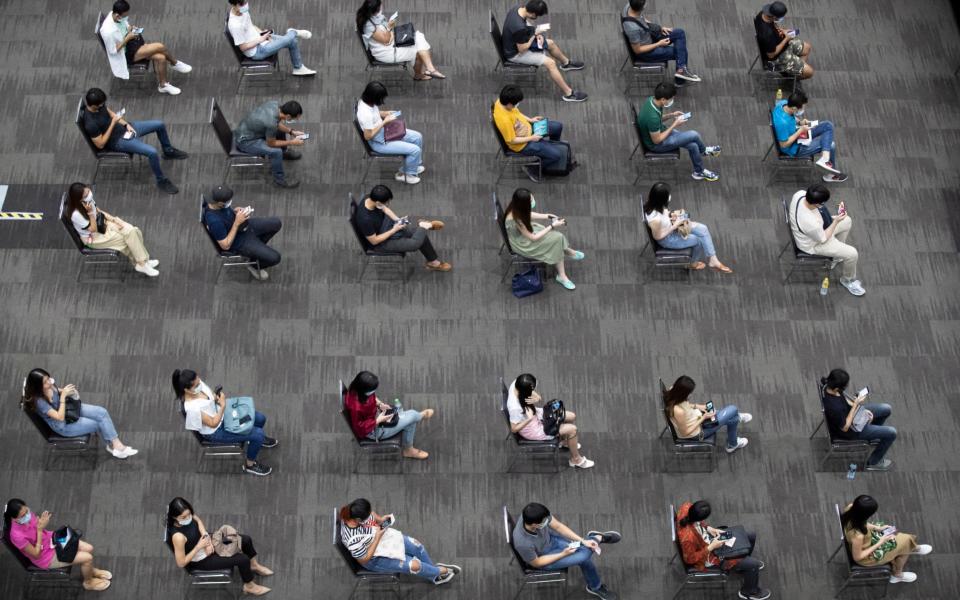 Airline employees sit after receiving the Sinovac COVID-19 vaccine to be sure of no side effects at the Siam Paragon shopping mall in Bangkok, Thailand - Sakchai Lalit/AP Photo