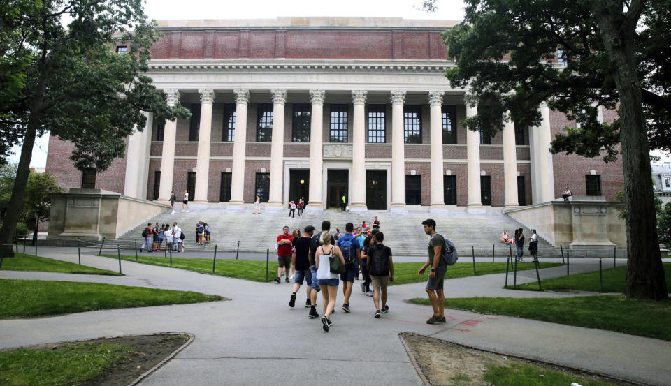 FILE - Students walk near the Widener Library at Harvard University in Cambridge, Mass., Aug. 13, 2019. Harvard University is telling students to take classes from home for three weeks, with a return to campus scheduled for late January, "conditions permitting." (AP Photo/Charles Krupa, File)