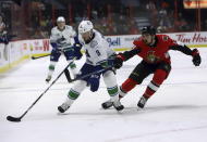 Vancouver Canucks center J.T. Miller (9) shields the puck away from Ottawa Senators left wing Nick Paul (13) during first-period NHL hockey action in Ottawa, Ontario, Thursday, Feb. 27, 2020. (Fred Chartrand/The Canadian Press via AP)