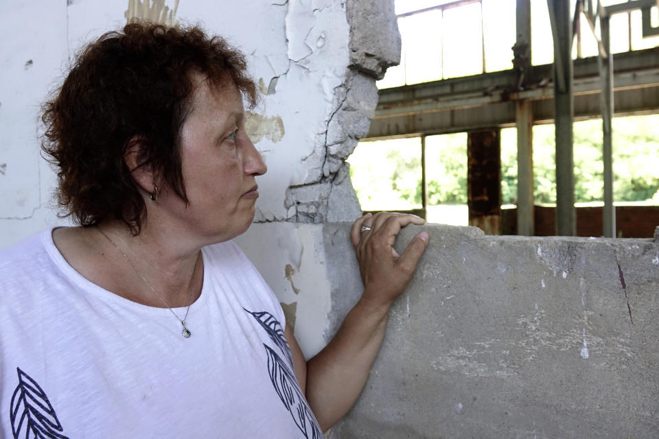 Devla Ajsic looks through the ruins of a former battery factory in Potocari near Srebrenica, Bosnia, Wednesday, July 7, 2021. Ajsic, who fled Srebrenica after being sexually abused in July 1995, has returned to live there, but says she is still afraid to walk through the town because she never knows if the people she encounters in the streets are genocide deniers or even took part in it. (AP Photo/Eldar Emric)