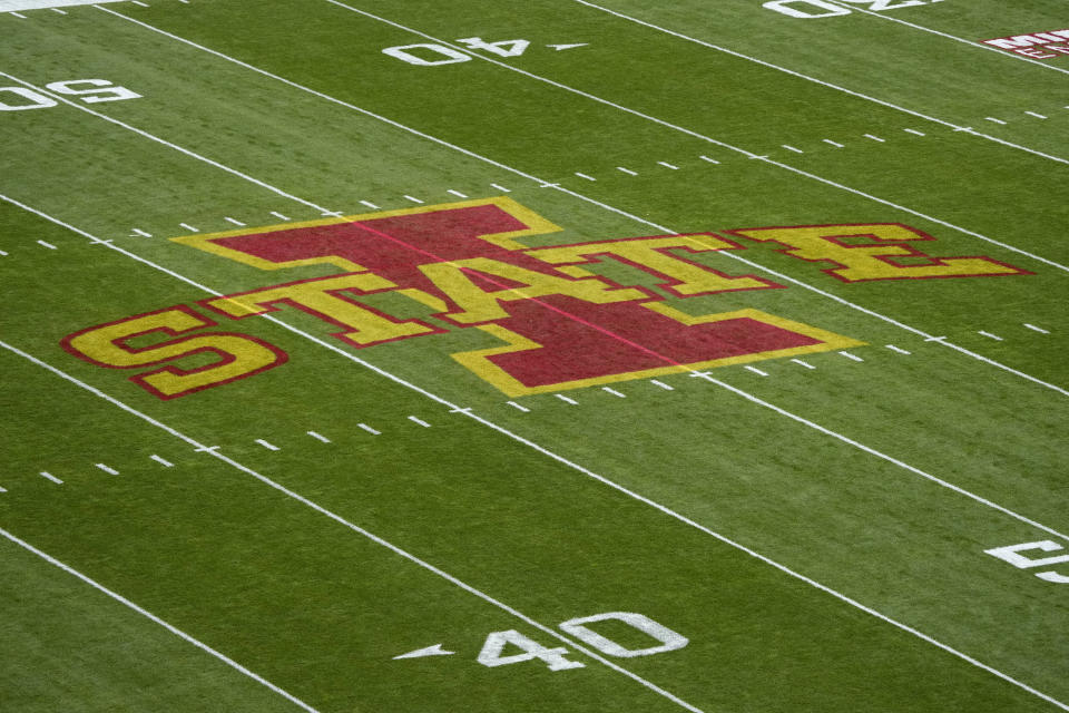 The Iowa State logo is seen on the field before an NCAA college football game against West Virginia, Saturday, Nov. 5, 2022, in Ames, Iowa. College athletic programs of all sizes are reacting to inflation the same way as everyone else. They're looking for ways to save. Travel and food are the primary areas with increased costs. (AP Photo/Charlie Neibergall)