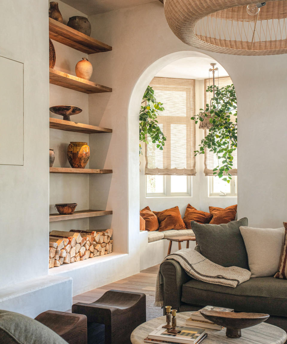 Rustic, neutral living room with arch doorway, wooden shelves in alcove, wooden flooring, cozy seating