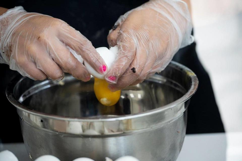 Baker Micaela Garcia, 20, of Merced, cracks eggs while preparing the ingredients for dough to make Molten Lava cookies at Crumbl Cookies, located at 3630 G Street, Suite E, in the new Yosemite Crossing shopping center in Merced, Calif., on Wednesday, June 7, 2023. The location’s grand opening is scheduled for June 9.