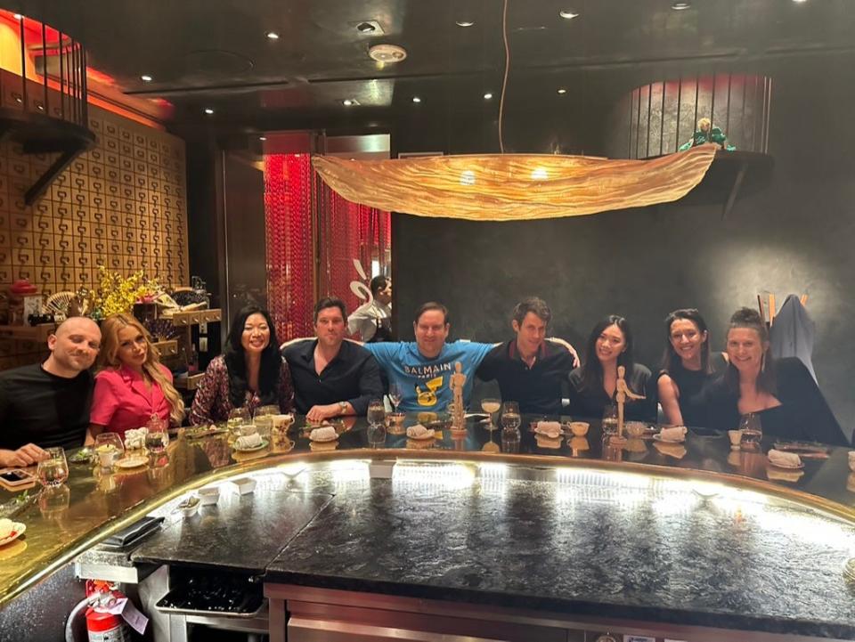 The author and his friends with drinks sitting around a curved table at a restaurant