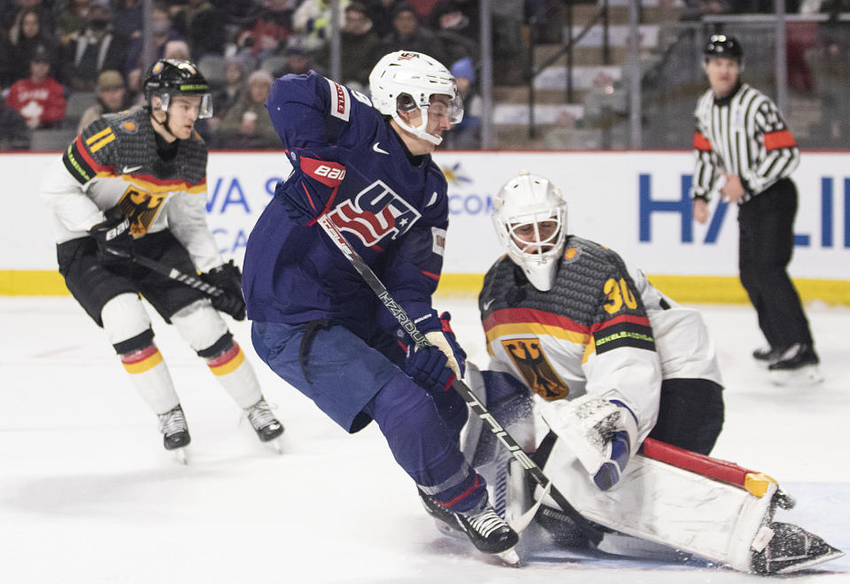 United States' Red Savage, front left, stuffs the puck past Germany's Nikitia Quapp, right, during second-period IIHF world junior hockey championships quarterfinal match action in Moncton, New Brunswick, Monday, Jan. 2, 2023. (Ron Ward/The Canadian Press via AP)