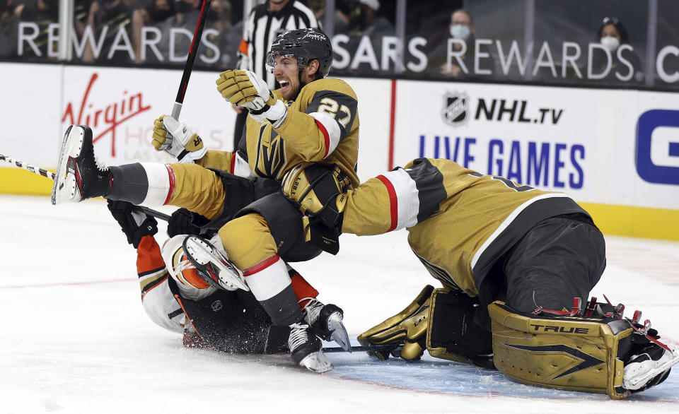 Vegas Golden Knights defenseman Shea Theodore (27) and goalie Marc-Andre Fleury (29) get taken down in a collision with Anaheim Ducks left wing Richard Rakell during the first period of an NHL hockey game Saturday, Jan. 16, 2021, in Las Vegas. (AP Photo/Isaac Brekken)