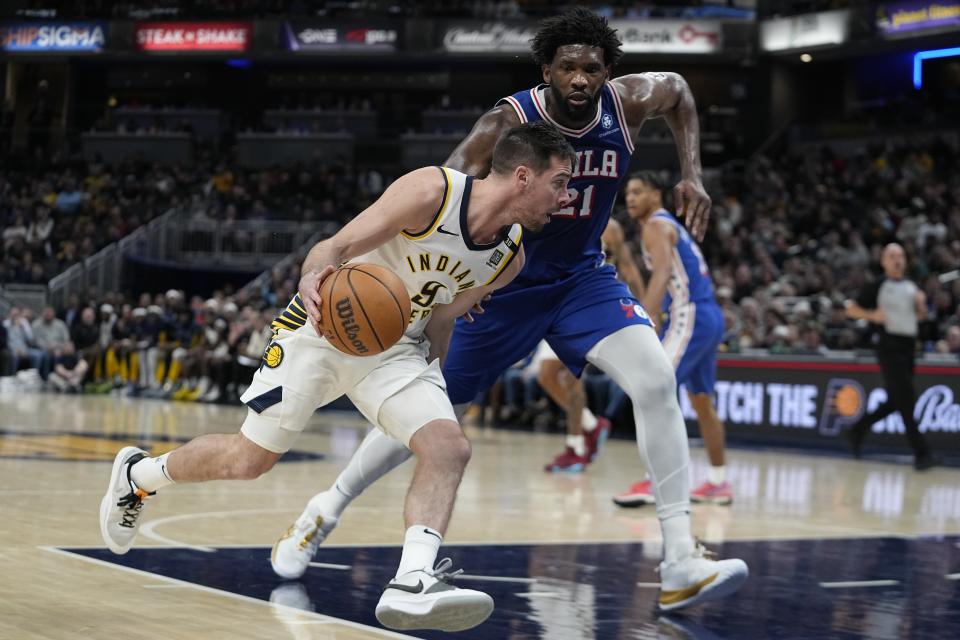 Indiana Pacers' T.J. McConnell (9) goes to the basket against Philadelphia 76ers' Joel Embiid (21) during the second half of an NBA basketball game Thursday, Jan. 25, 2024, in Indianapolis. (AP Photo/Darron Cummings)