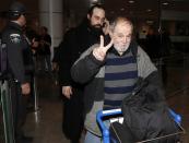 Raymond Paul gives a peace sign as he leaves the airport with his son, Canadian Greenpeace activist Alexandre Paul (back) in Montreal, December 27, 2013. Paul was detained in Russia for more than three months following a protest against Arctic oil drilling in international waters. REUTERS/Christinne Muschi (CANADA - Tags: ENVIRONMENT CIVIL UNREST CRIME LAW)