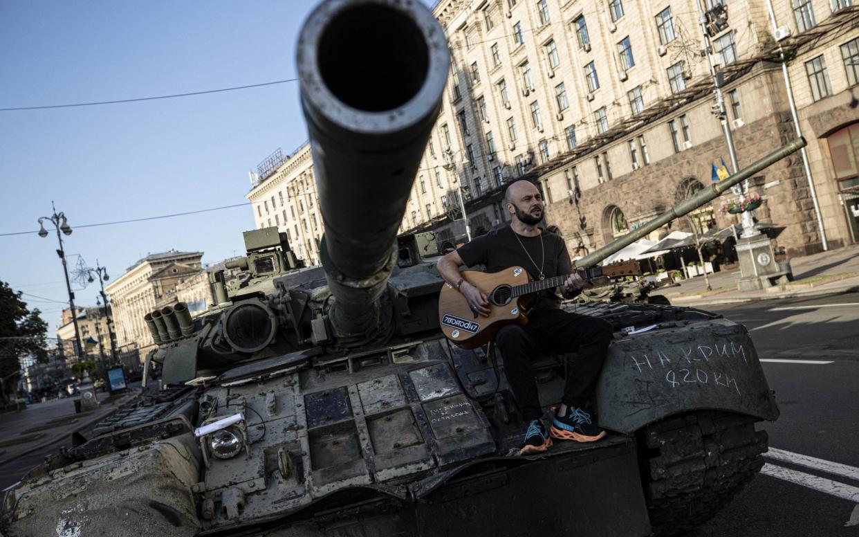 KYIV, UKRAINE - AUGUST 25: A man plays guitar on a tank captured from Russian army at the Khreschatyk Street in Kyiv, Ukraine on August 25, 2022 as Russia-Ukraine war continues. Ukraine marked the 31st anniversary of its independence from the Soviet Union as the war with Russia entered its seventh month. (Photo by Metin Aktas/Anadolu Agency via Getty Images) - Metin Aktas/Anadolu Agency via Getty Image