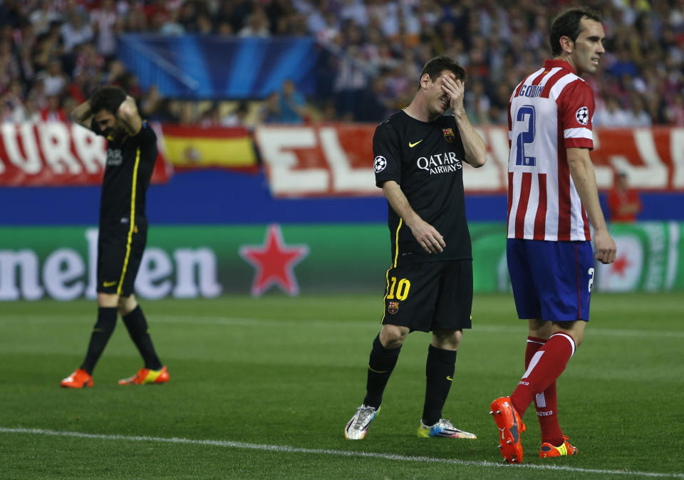 Barcelona's Lionel Messi and Cesc Fabregas react next to Atletico's Diego Godin, right, during the Champions League quarterfinal second leg soccer match between Atletico Madrid and FC Barcelona at the Vicente Calderon stadium in Madrid, Spain, Wednesday, April 9, 2014. (AP Photo/Andres Kudacki)