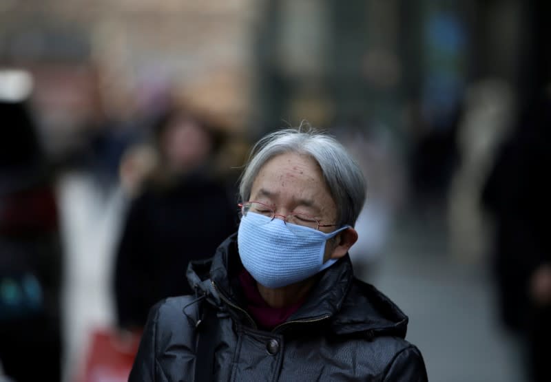 Woman wearing a mask walks along a street in Beijing