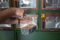 A Go Noodles box is taken by an employee from a glass-paned locker in Tel Aviv, Israel, Thursday, July 16, 2020. The coronavirus crisis and its economic impact have forced many small businesses and restaurants to shut their doors in recent months, but Tel Aviv's Go Noodles opened a new branch last week that features digital-only ordering and pickup from lockers. (AP Photo/Ariel Schalit)