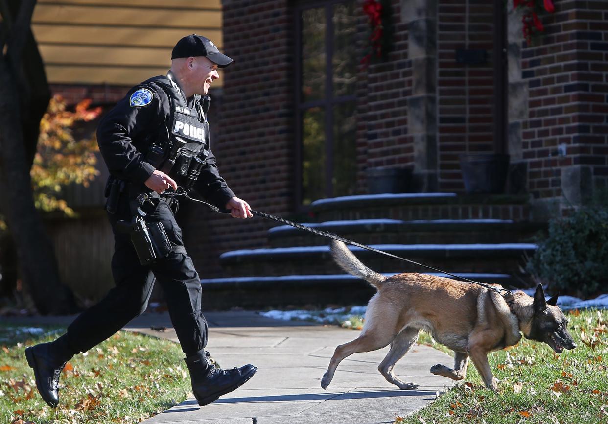 Officer Jeff Edsall, left, races his K-9 partner Justice back to the cruiser after the pair showed reporters where an arrest was made on Firestone Boulevard in Akron.