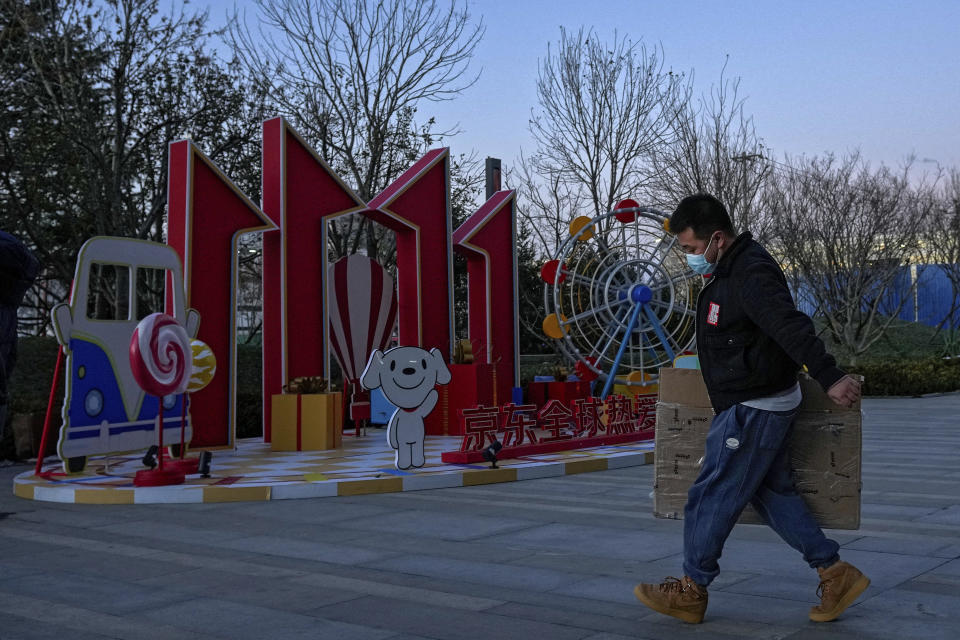 A man wearing a face mask to help protect from the coronavirus walks by a promotional display celebrating the online shopping day, known as "Singles' Day" outside the Chinese online retailer JD.com's headquarter in Beijing on Tuesday, Nov. 9, 2021. China's biggest online shopping day, known as "Singles' Day" on Nov. 11, is taking on a muted tone this year amid a regulatory crackdown on the technology industry and President Xi Jinping's push for "common prosperity." (AP Photo/Andy Wong)