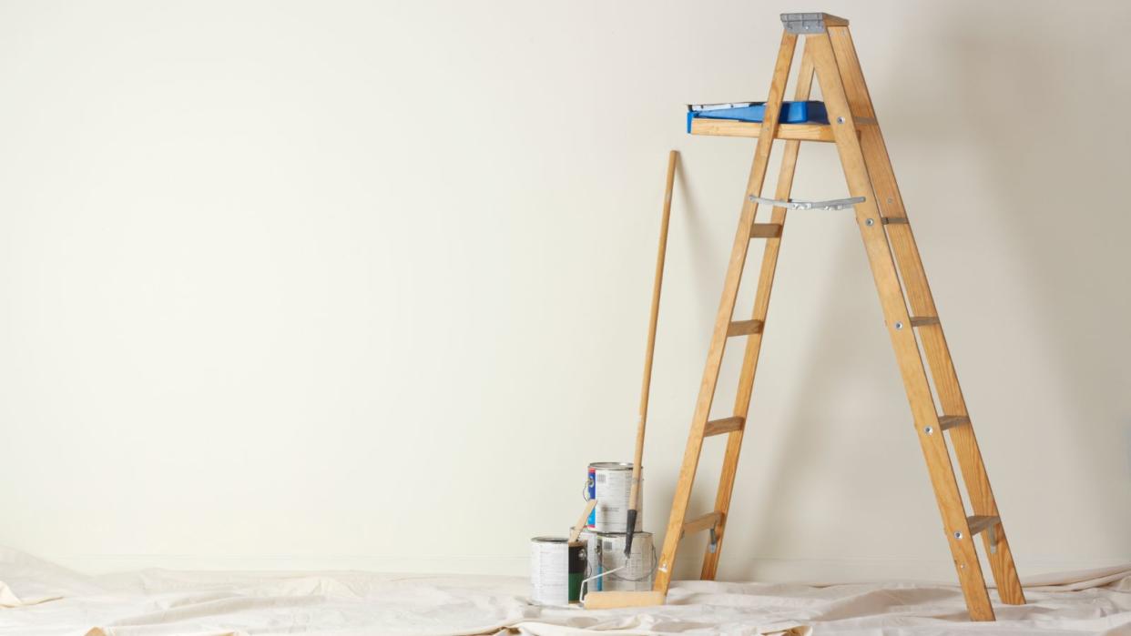  Ladder in a room in front of a black wall with some painting tools 