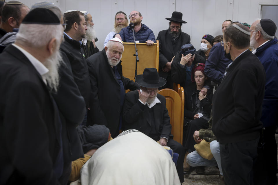 Mourners gather around the body of Yehuda Dimentman, 25, during his funeral in Givat Shaul cemetery in Jerusalem, Friday, Dec. 17, 2021. Palestinian gunman opened fire Thursday night at a car filled with Jewish seminary students next to a West Bank settlement outpost, killing Yehuda Dimentman and lightly wounding two other people, Israeli officials said. (AP Photo/Oren Ziv)