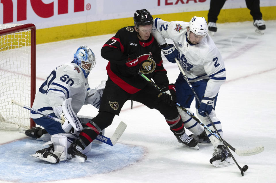 Toronto Maple Leafs defenseman Simon Benoit (2) deflects the puck away from Ottawa Senators left wing Brady Tkachuk (7) and Maple Leafs goaltender Joseph Woll, left, during first-period NHL hockey game action Thursday, Dec. 7, 2023, in Ottawa. (Adrian Wyld/The Canadian Press via AP)