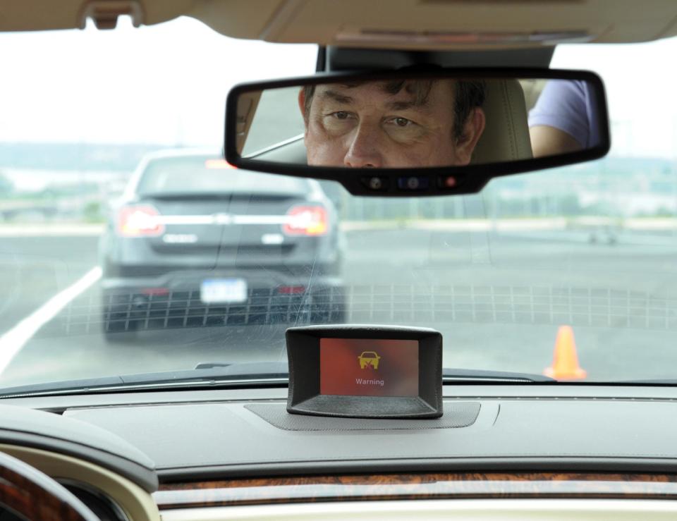 In this photo taken, Tuesday, May 22, 2012, professional test driver Dave McMillan, from Los Angeles, demonstrates the dashboard warning signal in a Buick Lacrosse at an automobile test area in Oxon Hill. The display at a recent transportation conference was a peek into the future of automotive safety: cars that to talk to each other and warn drivers of impending collisions. Later this summer, the government is launching a yearlong, real-world test involving nearly 3,000 cars, trucks and buses using volunteer drivers in Ann Arbor, Mich. (AP Photo/Susan Walsh)